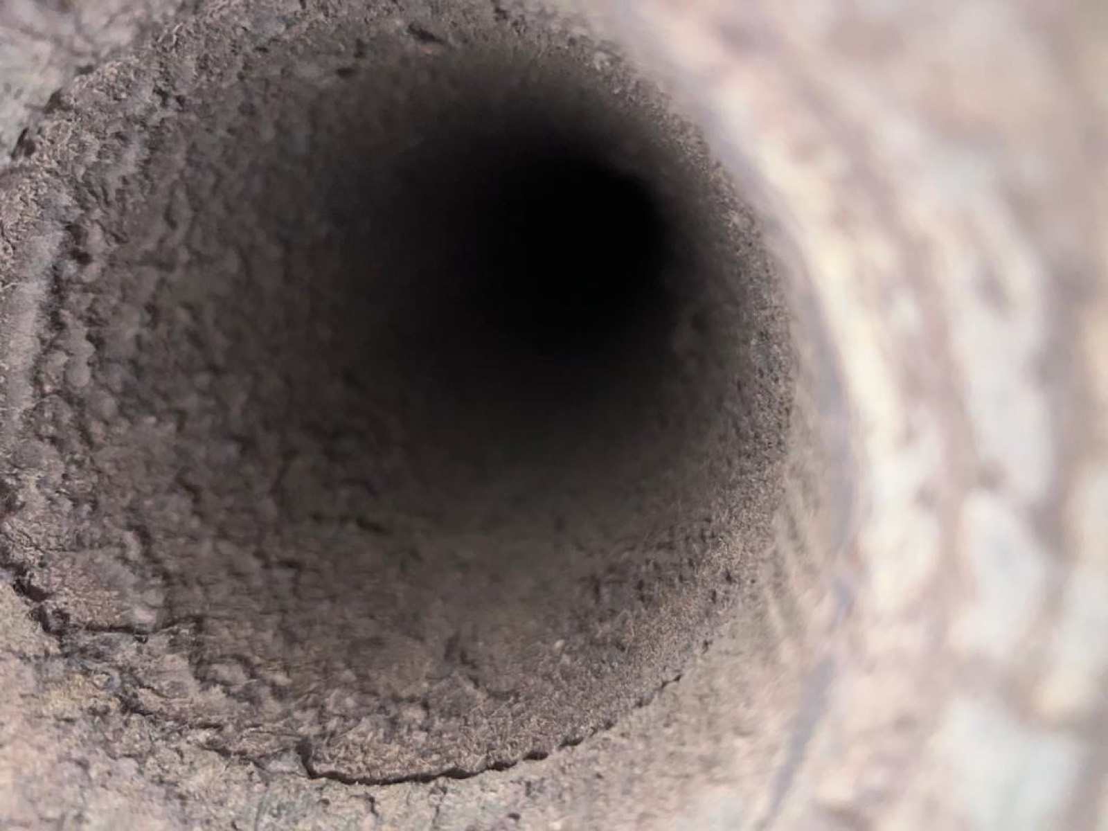 Inside a dryer duct with lint coating the walls before cleaning